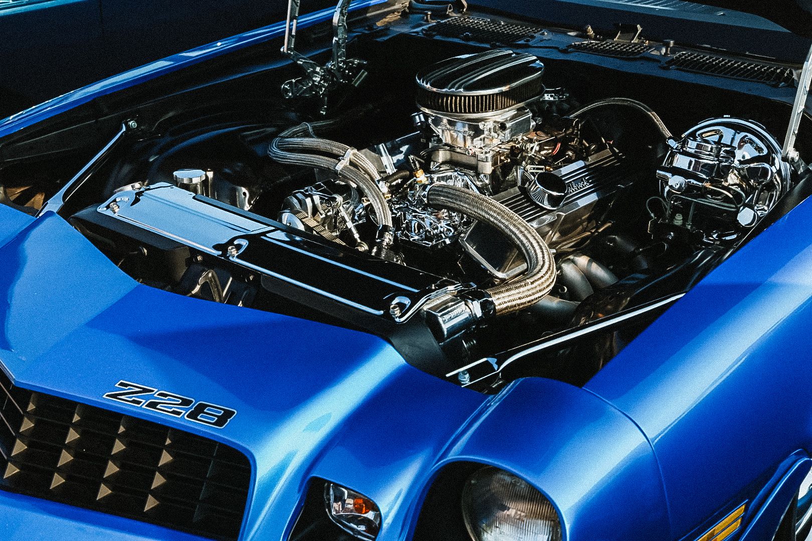 Under hood view of a performance engine in a blue muscle car.