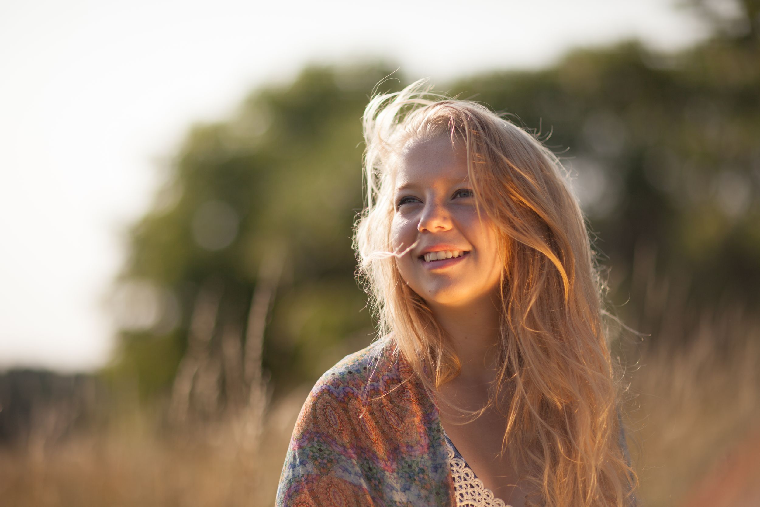 Golden hour portrait with soft backlighting and flowing hair in natural outdoor setting.