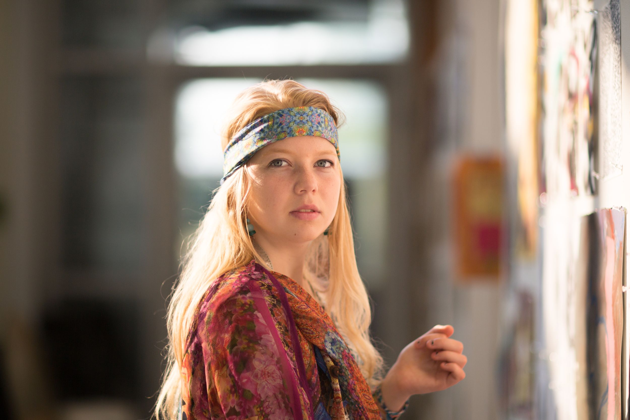 Artistic portrait featuring bohemian style clothing and headband in natural indoor lighting.