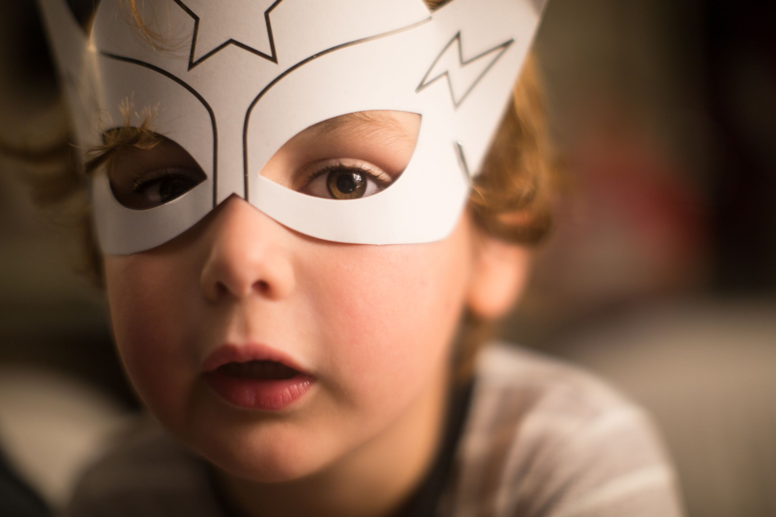 Close-up shot of a paper superhero mask with hand-drawn lightning bolt and star designs.