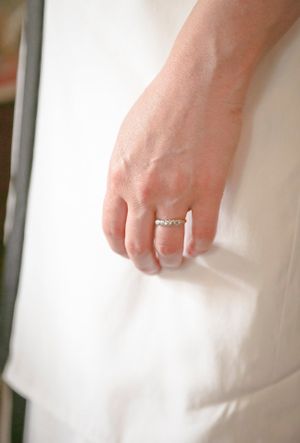 Close-up detail of hands in white fabric showing an engagement ring.
