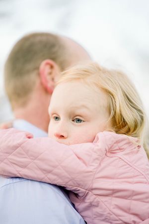 A tender moment captured as a child in pink rests against someone wearing blue.
