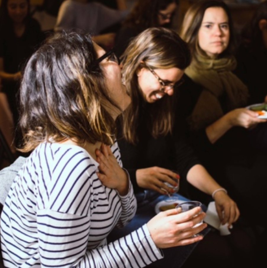 People enjoying coffee and conversation in a dimly lit casual setting.