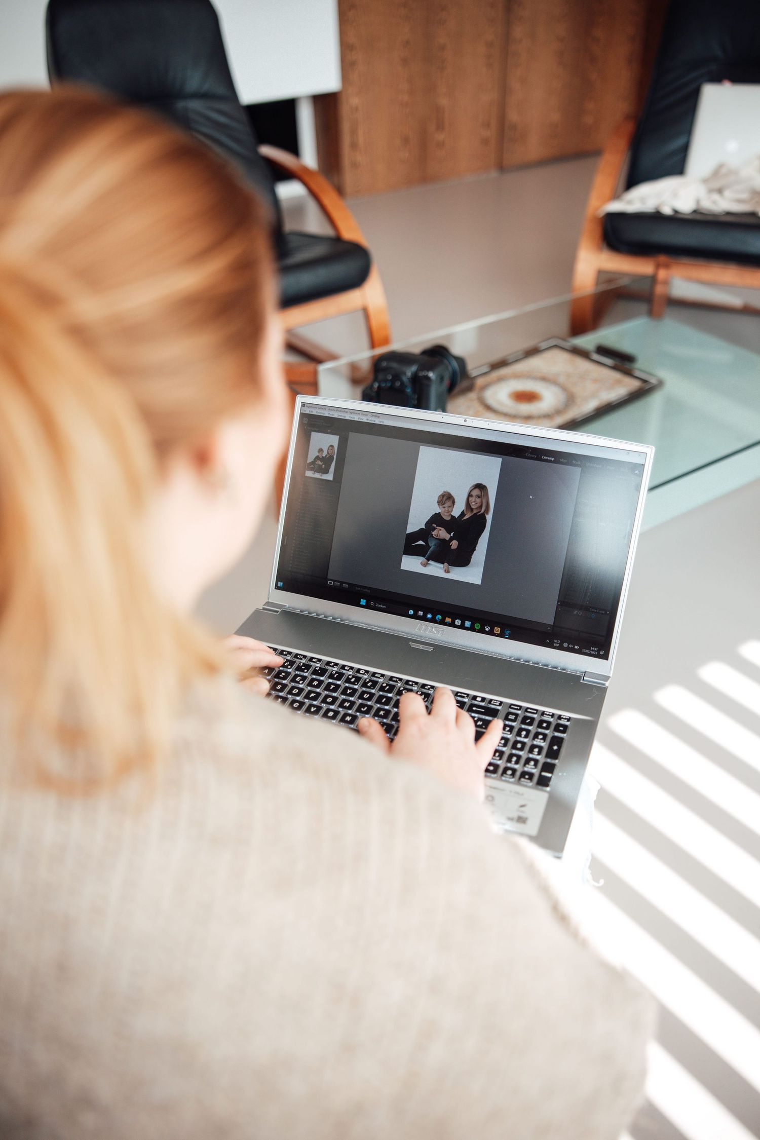 Person viewing video call on laptop in sunlit room with shadow patterns.