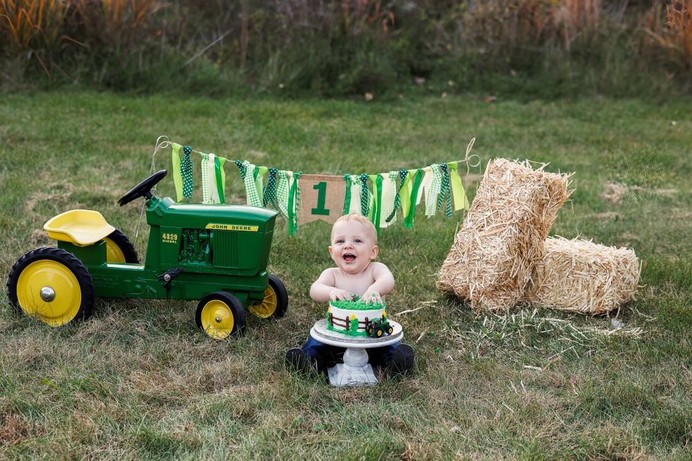 Festive outdoor scene with John Deere tractor, cake, and decorative green banners.