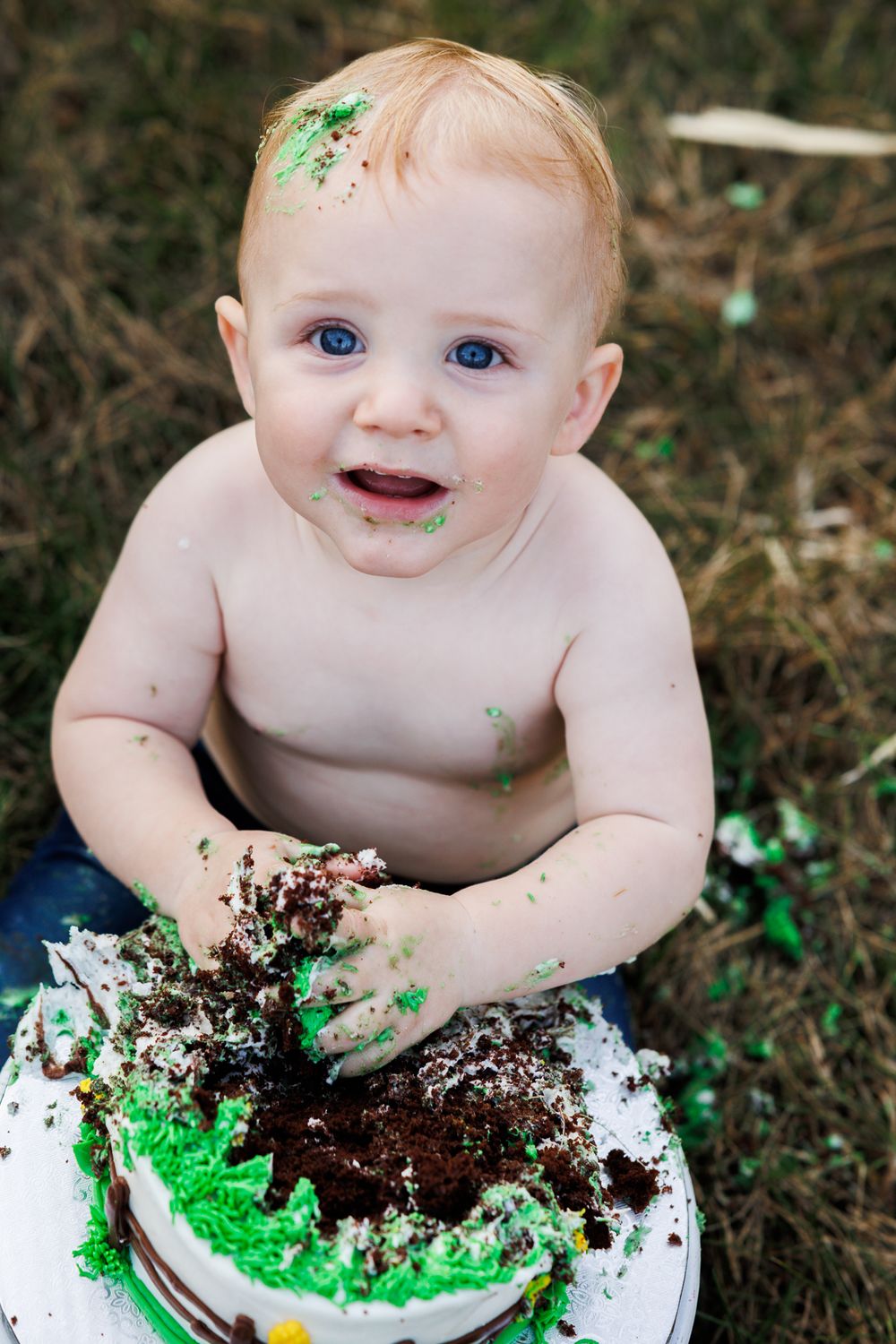 Messy cake smash photo with green frosting and playful expressions.