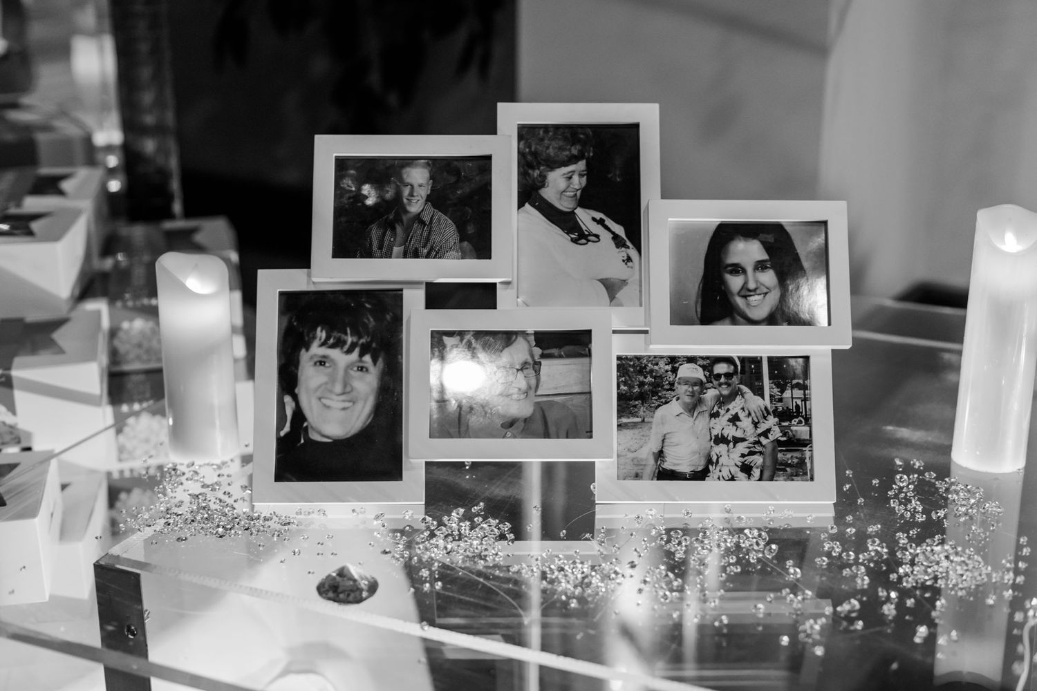 Black and white photo display wall featuring multiple framed photographs at a wedding celebration.