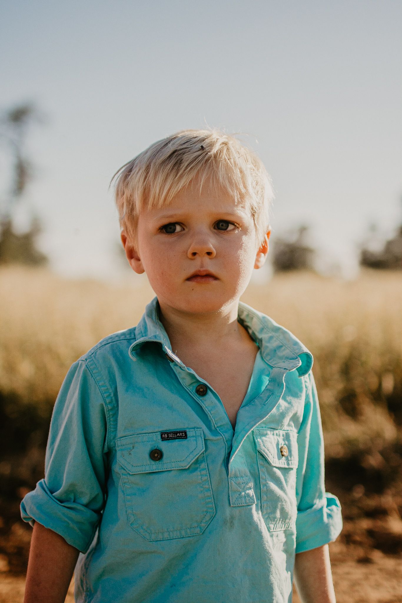 Farm boy in a work shirt standing in a paddock