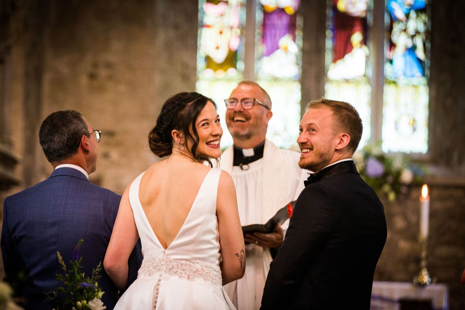 Joyful exchange during wedding ceremony in church with stained glass windows.