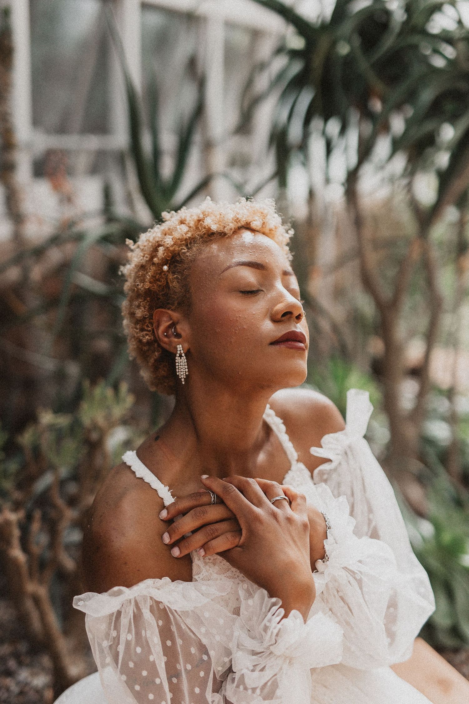 An ethereal bridal portrait in a greenhouse with soft lighting and delicate lace details.