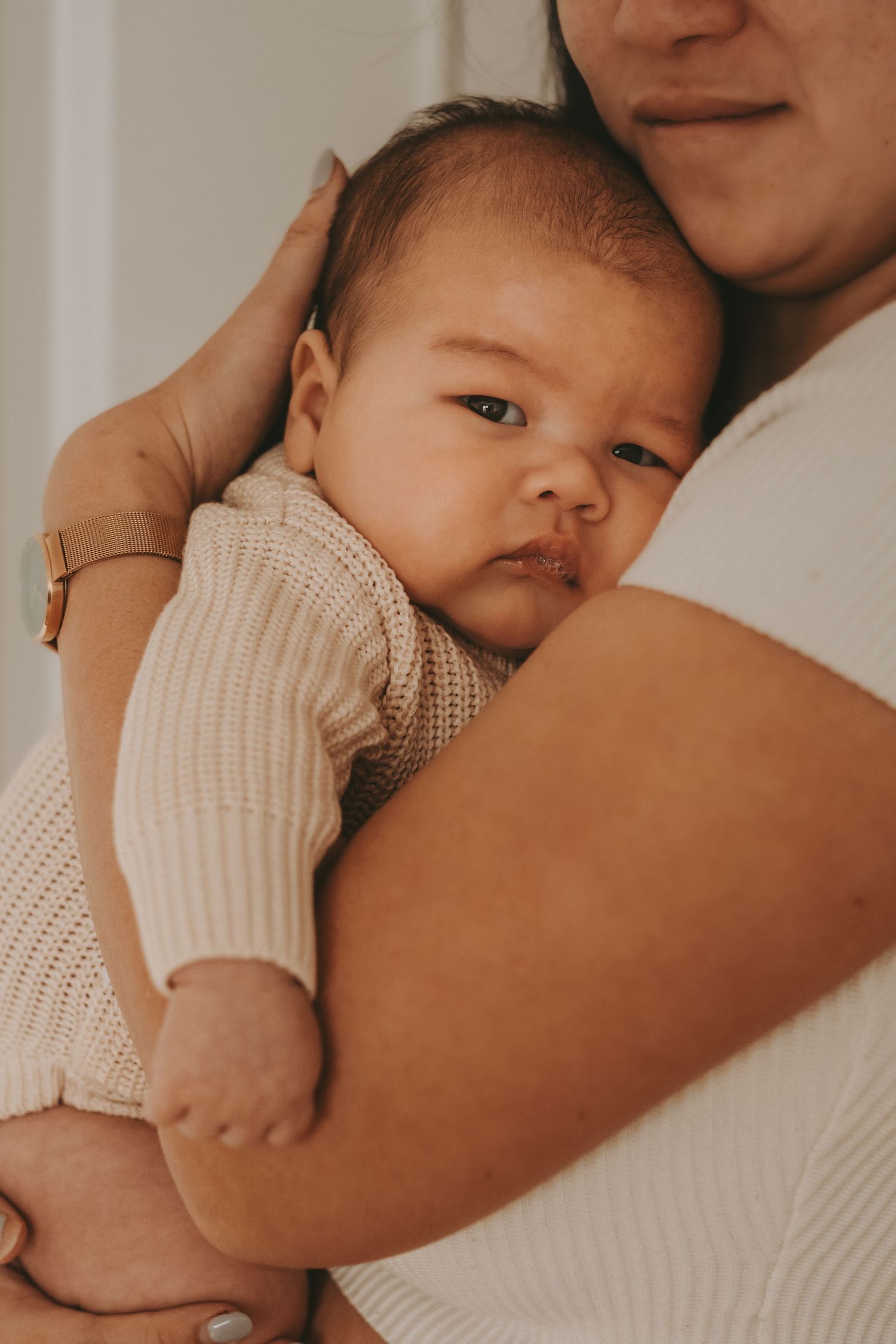 A sweet baby in a cream knit sweater snuggles close during a tender moment.