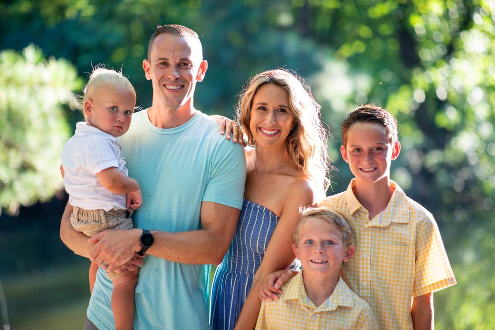 Happy family of five poses together outdoors on a sunny summer day.