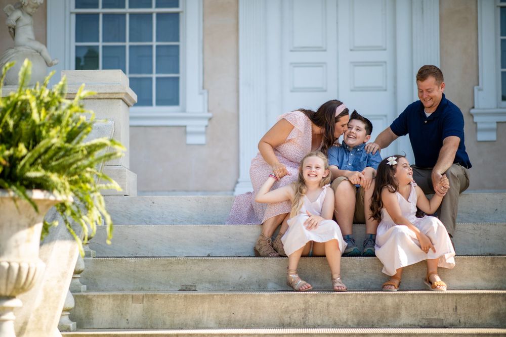 Family sitting together on outdoor stone steps sharing candid moment.
