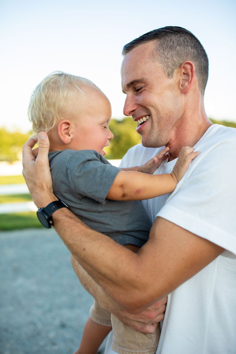 Parent and toddler share joyful moment together outdoors in warm sunlight.