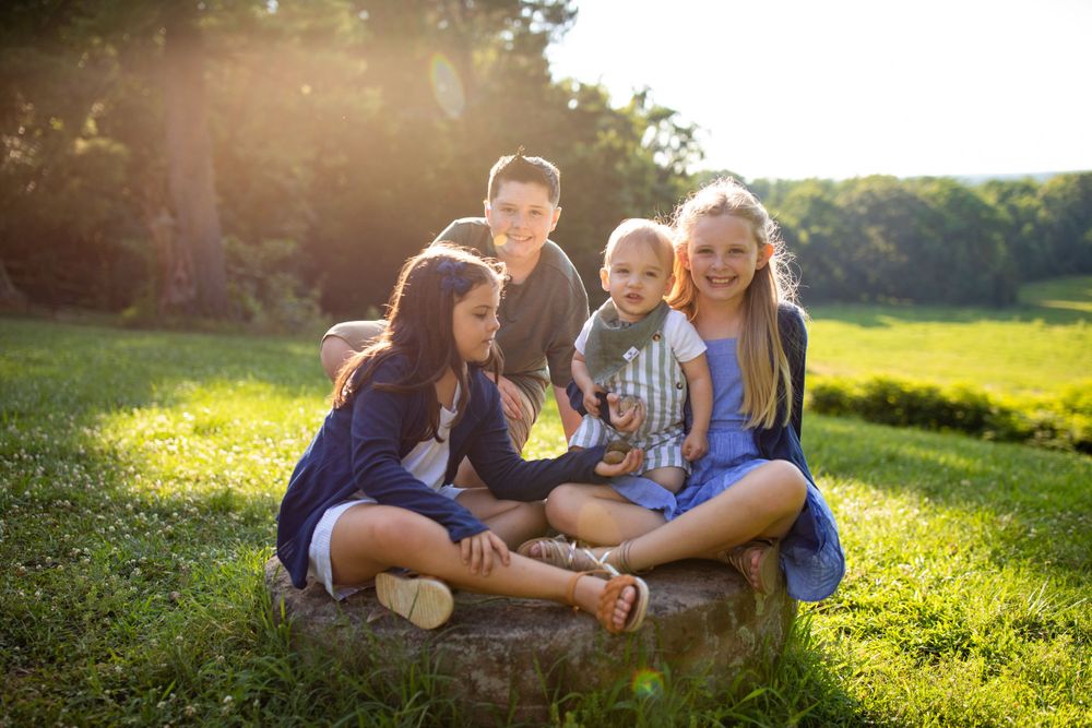 A group sits together on a rock in a sunlit field during golden hour.