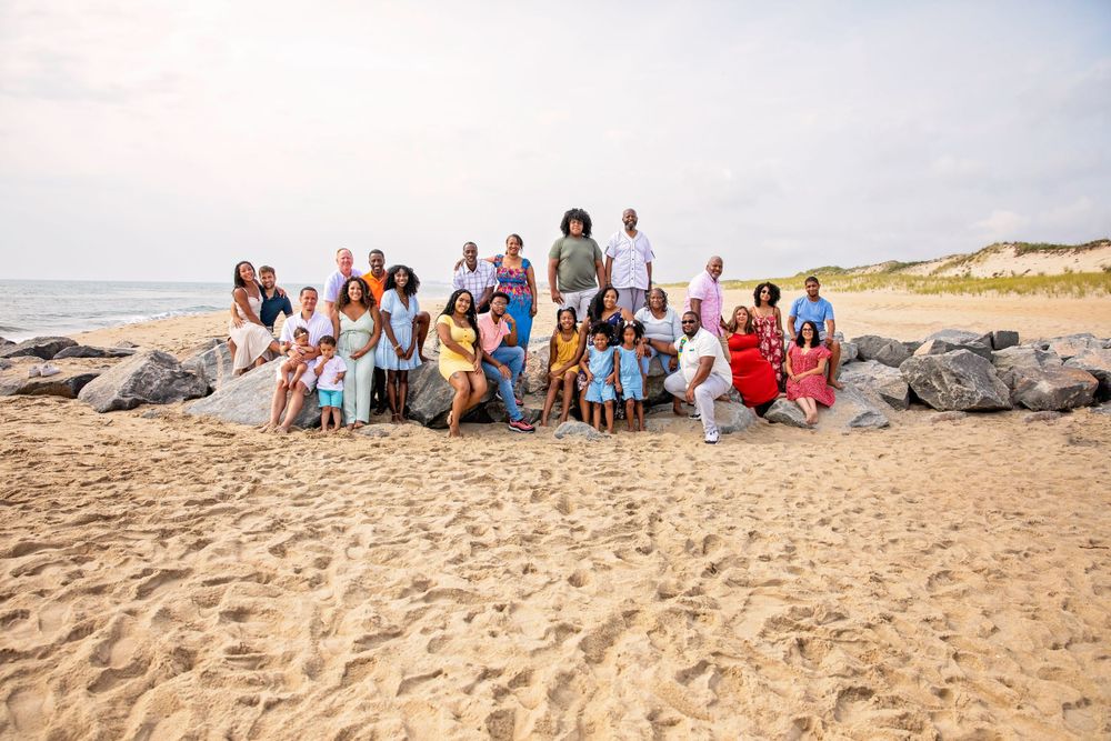 Large group gathered on beach rocks for a casual outdoor photo session.