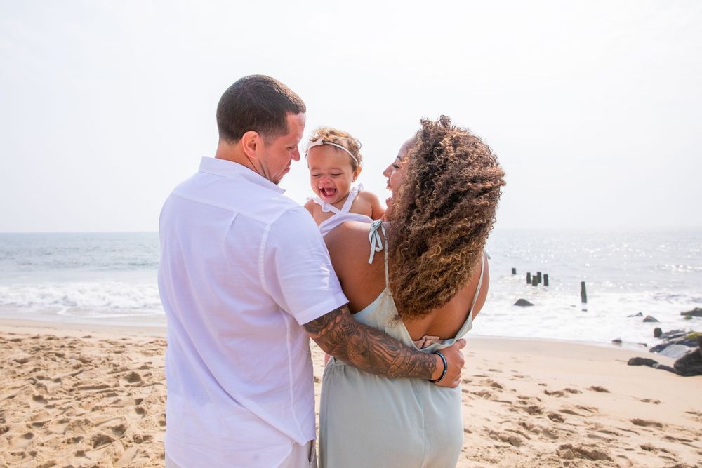 A family shares an intimate moment together on a beach with waves in the background.