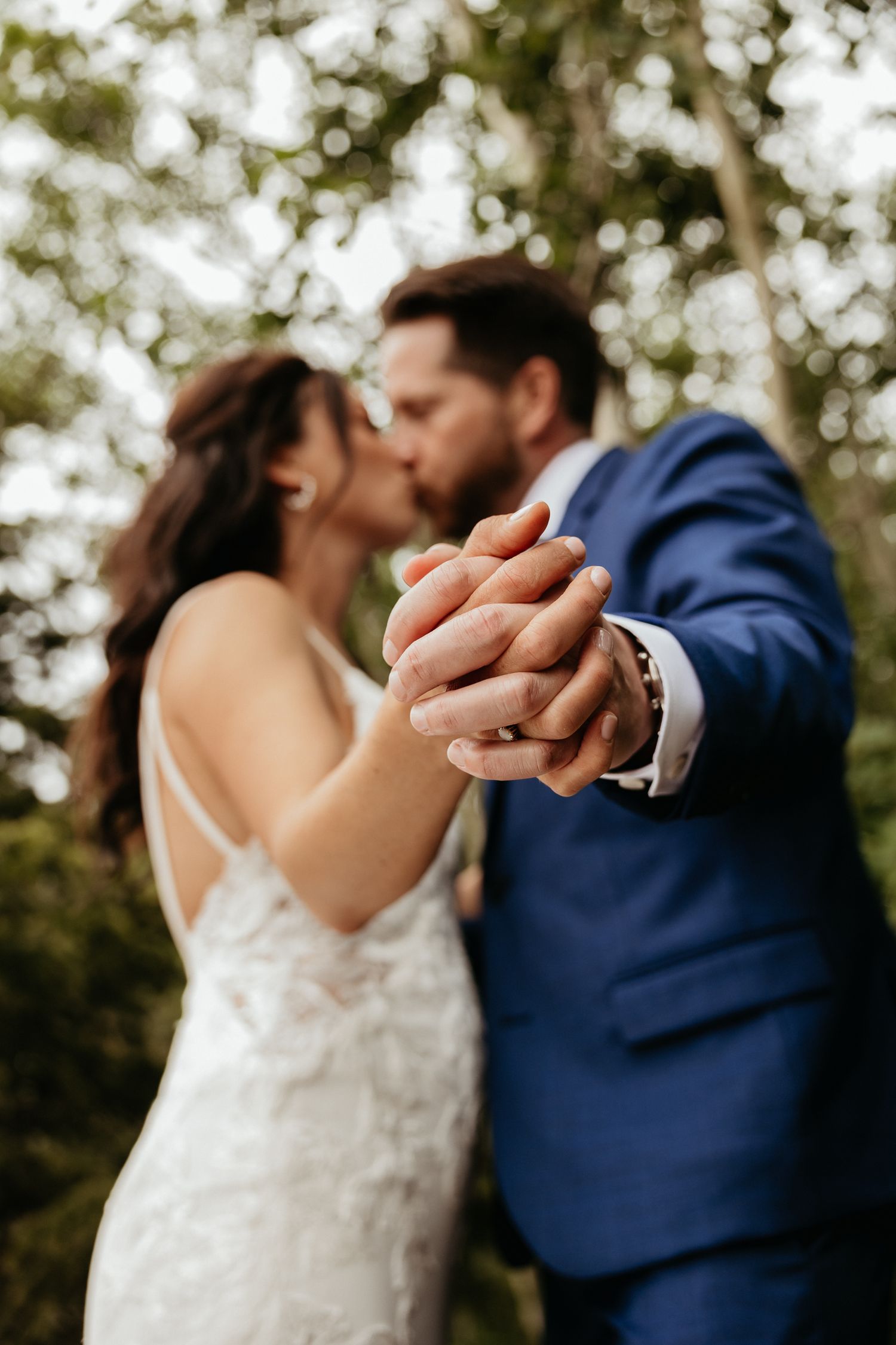Close-up of a couple dancing in a romantic pose with a blue suit and white dress.