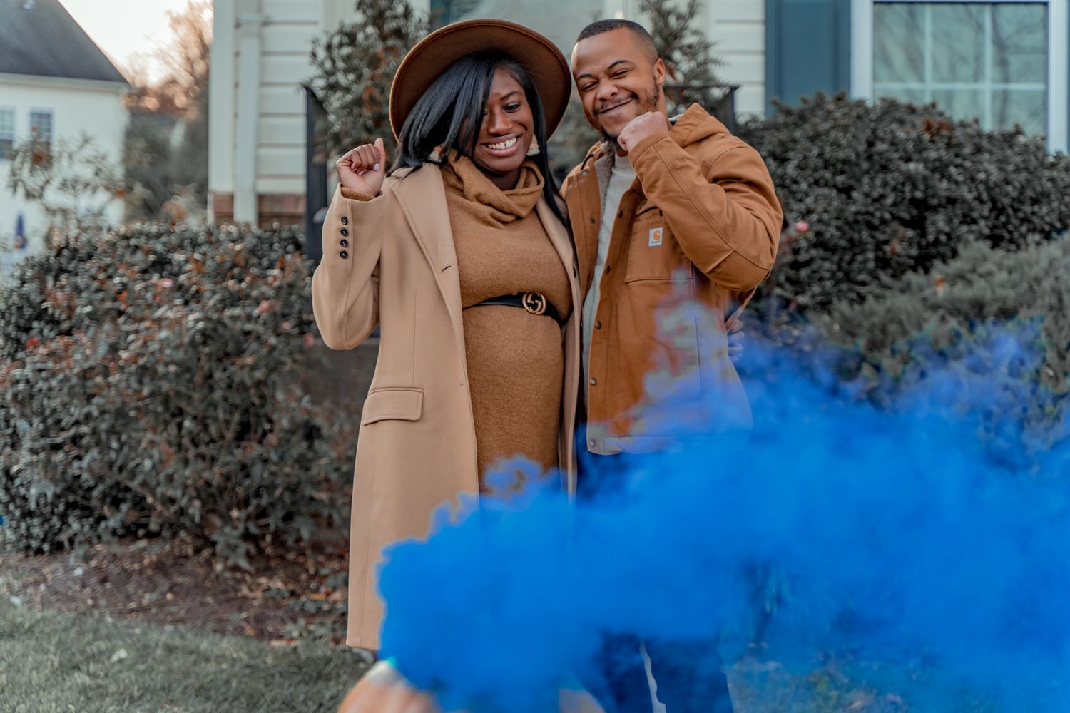 Couple celebrating with blue smoke bombs in front of their house.