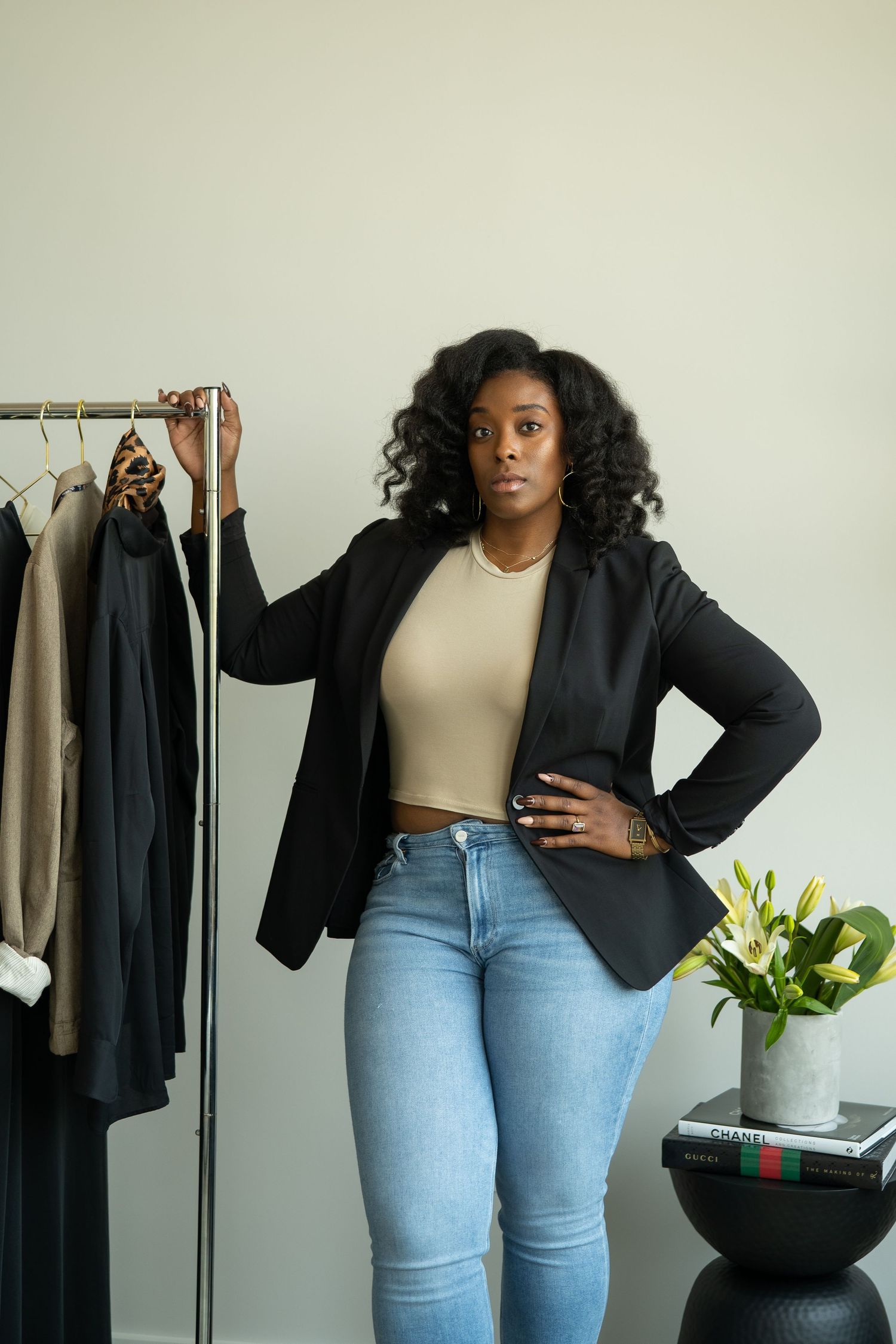 Sanetra Longno photo of Jazzmyne Karr posted next to a clothing rack of garments and books with lily on side table