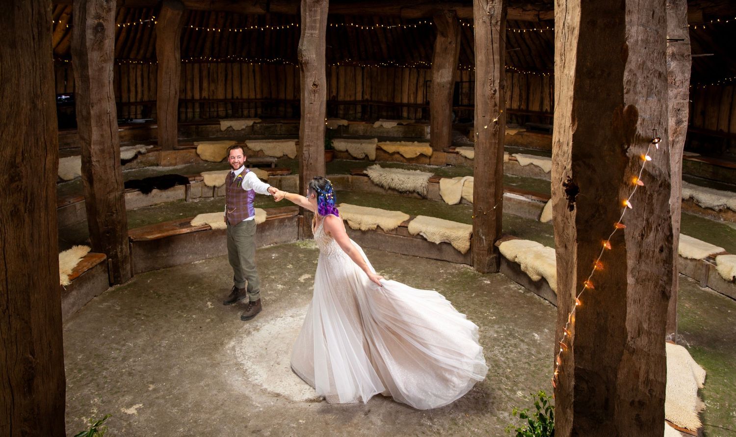 A white dress creates a spinning motion effect in a circular wooden structure with string lights.