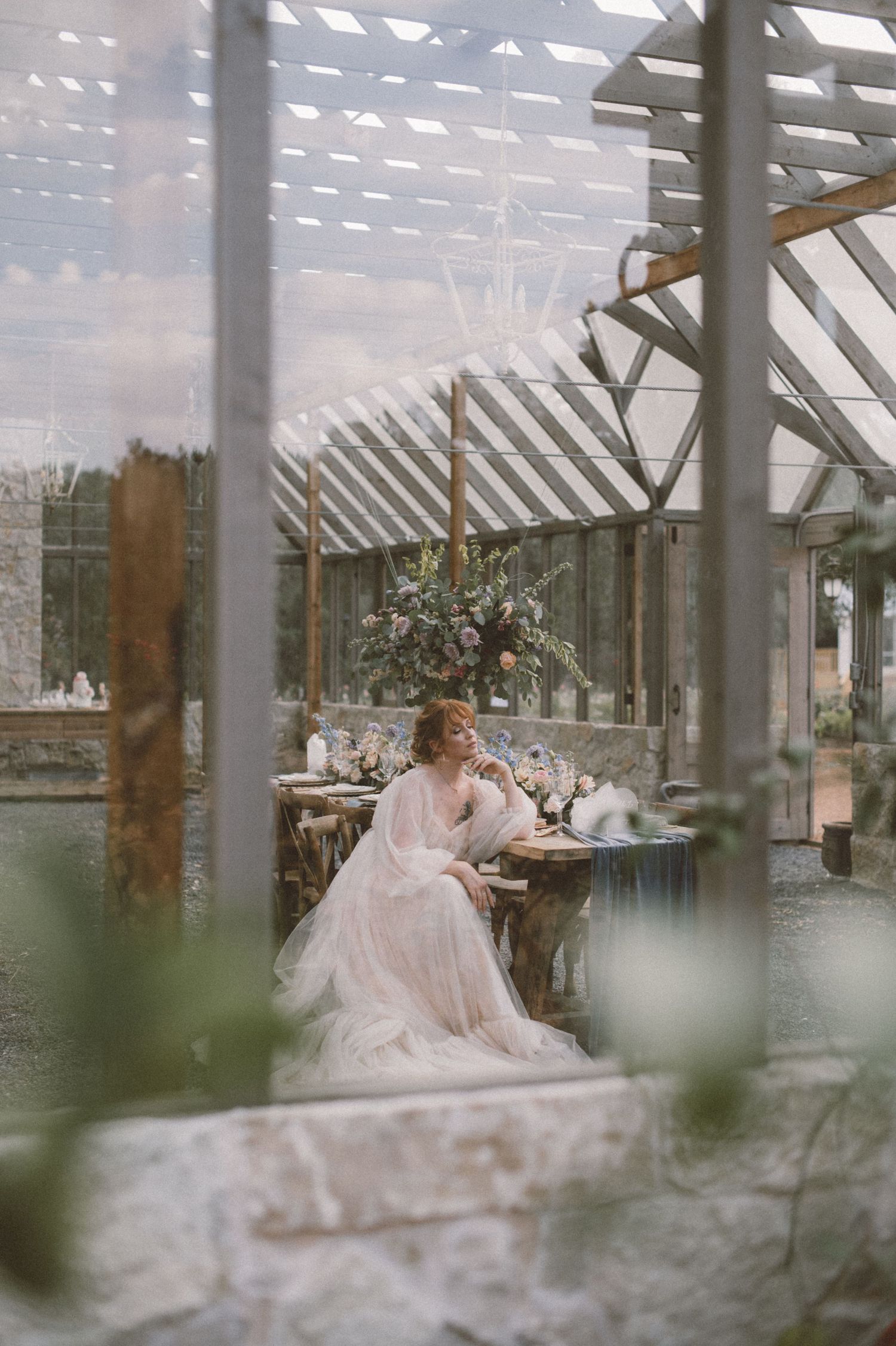 Dreamy greenhouse wedding setup with white dress and natural light streaming through glass panels.
