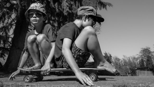 Two boys share one skateboard in a north Vancouver outdoor lifestyle family photo