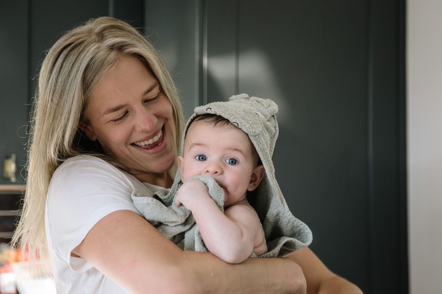 A joyful moment between parent and baby wearing a knit hat against a dark background.