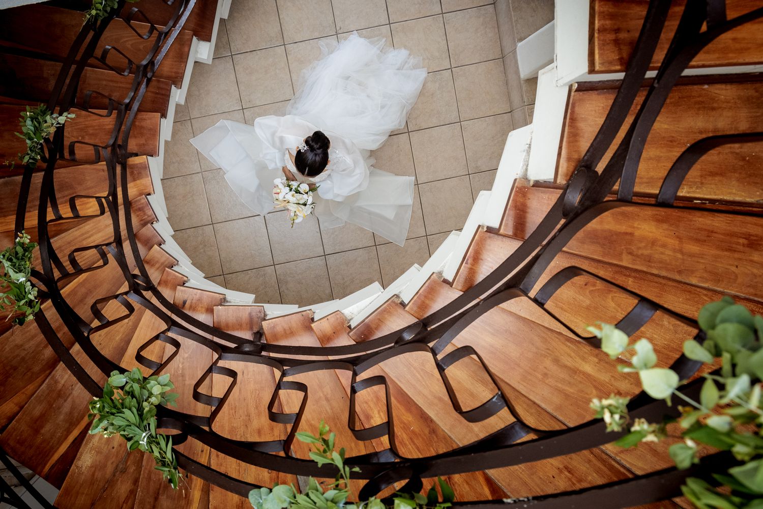 Spiral staircase decorated with white flowers and greenery for wedding ceremony.