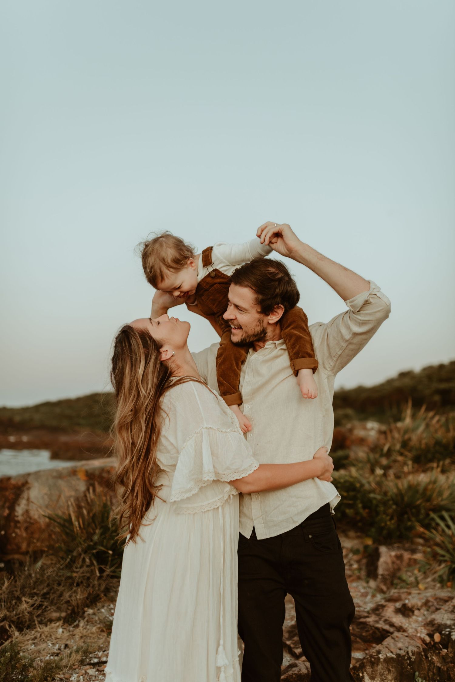 Family shares joyful moment together during sunset photoshoot on rocky terrain.