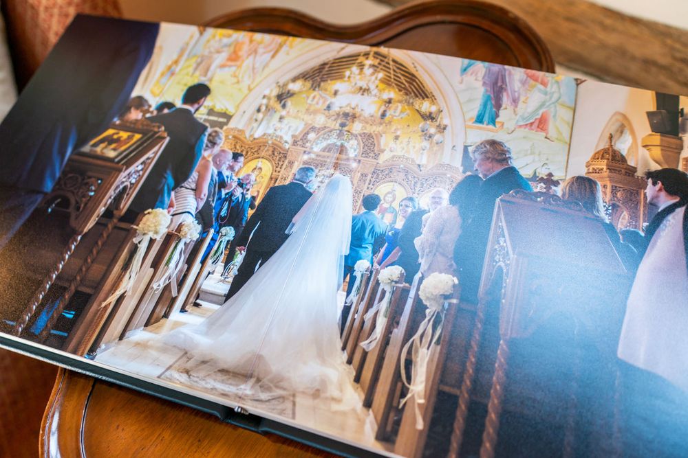 Wedding ceremony photograph in church showing aisle and guests in photo album spread.