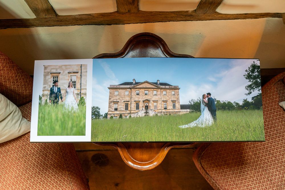 Wedding album spread showing elegant mansion venue with couple on lawn.