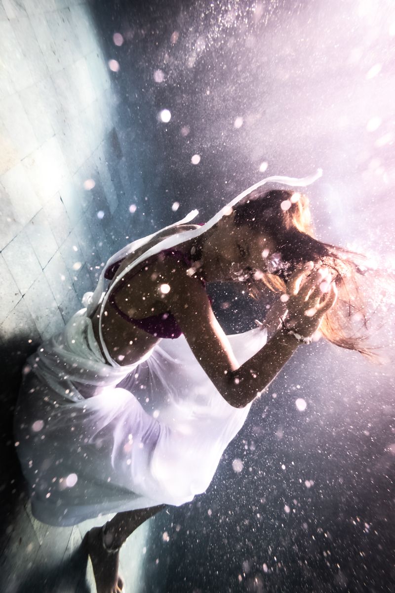 Girl in a white dress smiles underwater