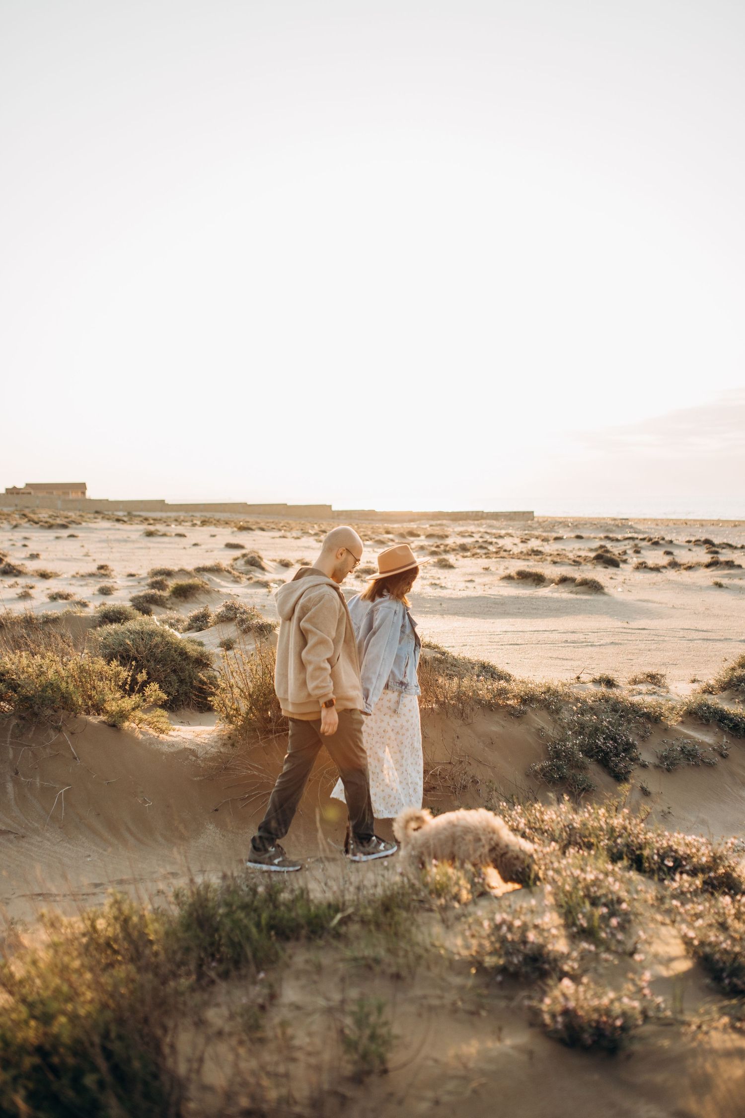 Couple walking together in desert landscape during golden hour.