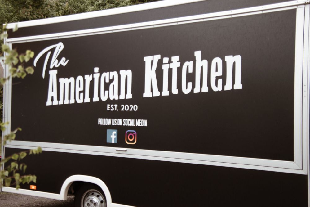 Black and white signage for 'The American Kitchen' on a food truck exterior.