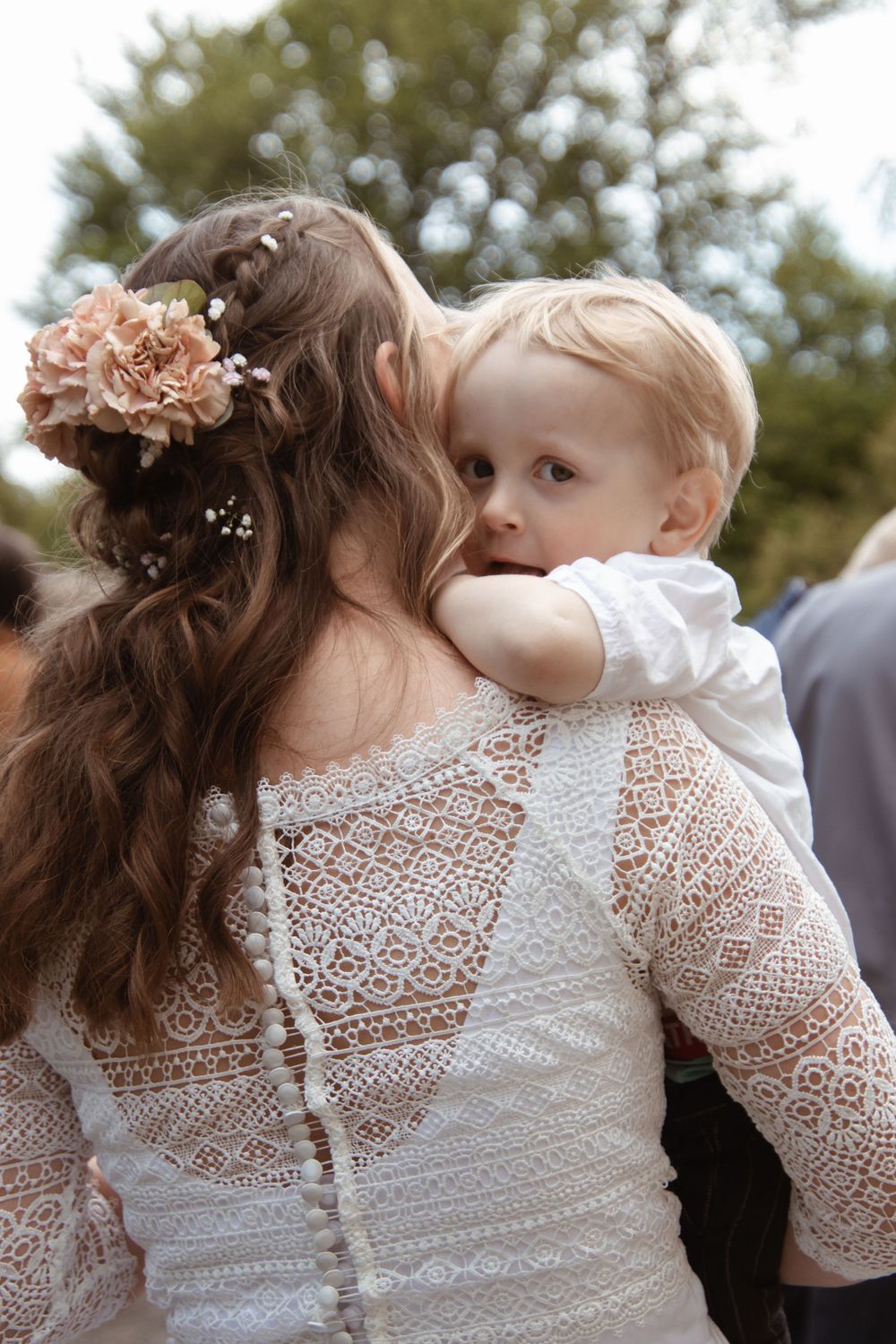 A detailed view of a lace wedding dress back with floral hair accessories.