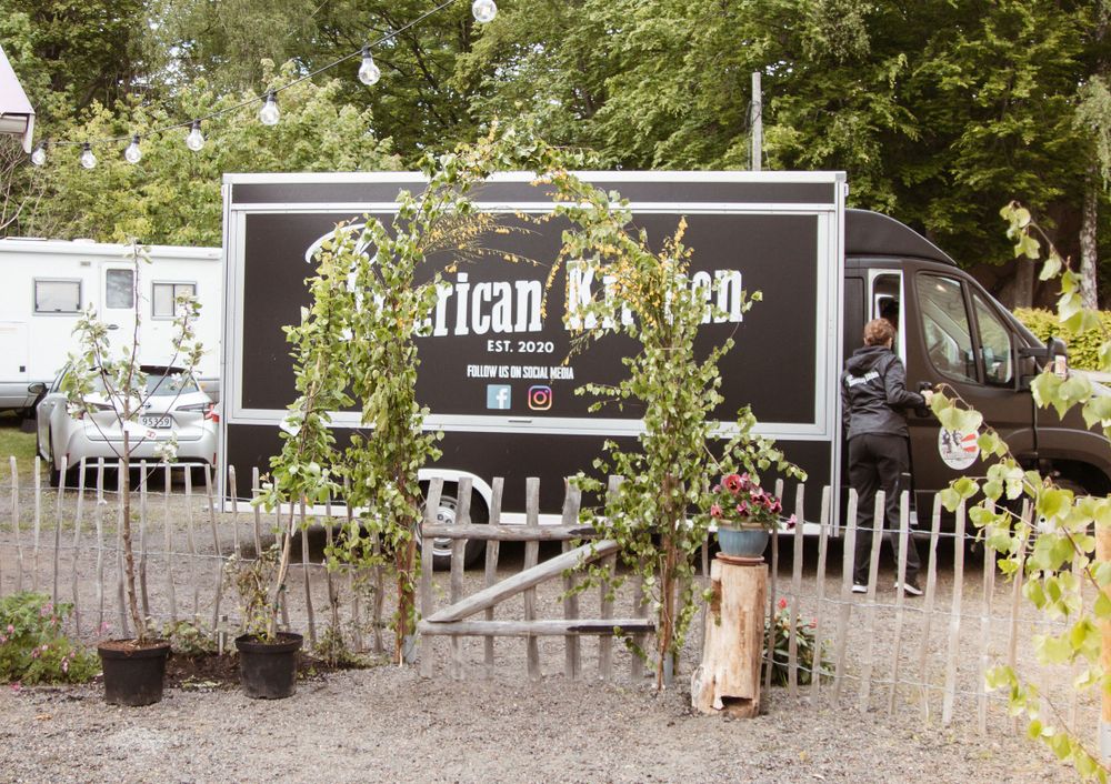 A food truck decorated with greenery and vines parked outdoors.