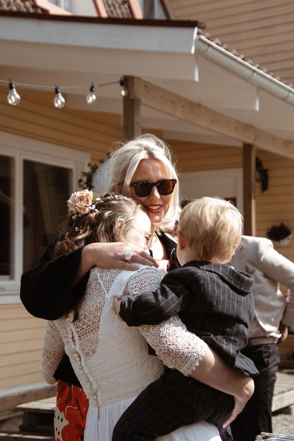 A warm family moment captured on a sunny porch with string lights in the background.