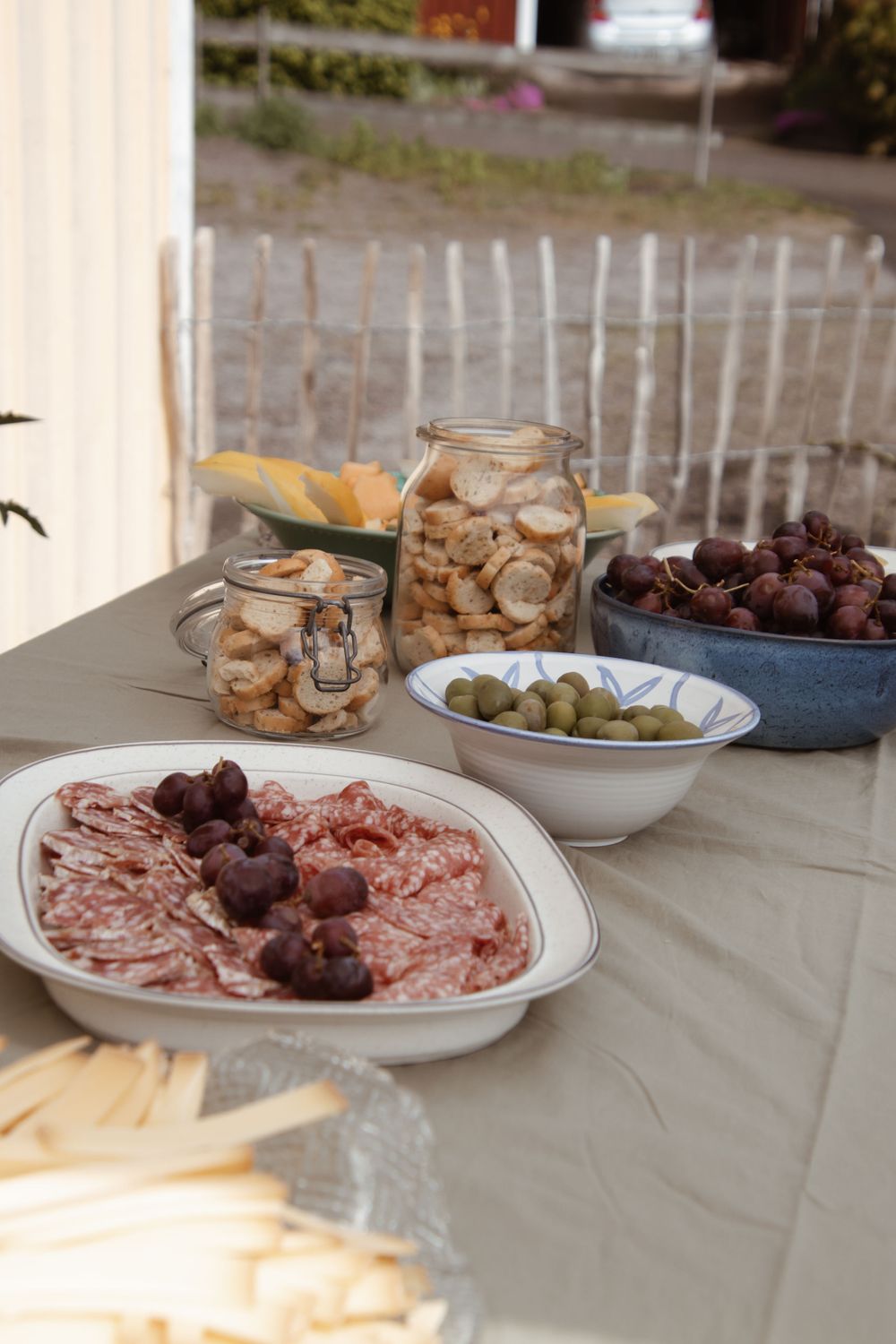 Charcuterie spread featuring meats, olives, and preserved items on a grey tablecloth.