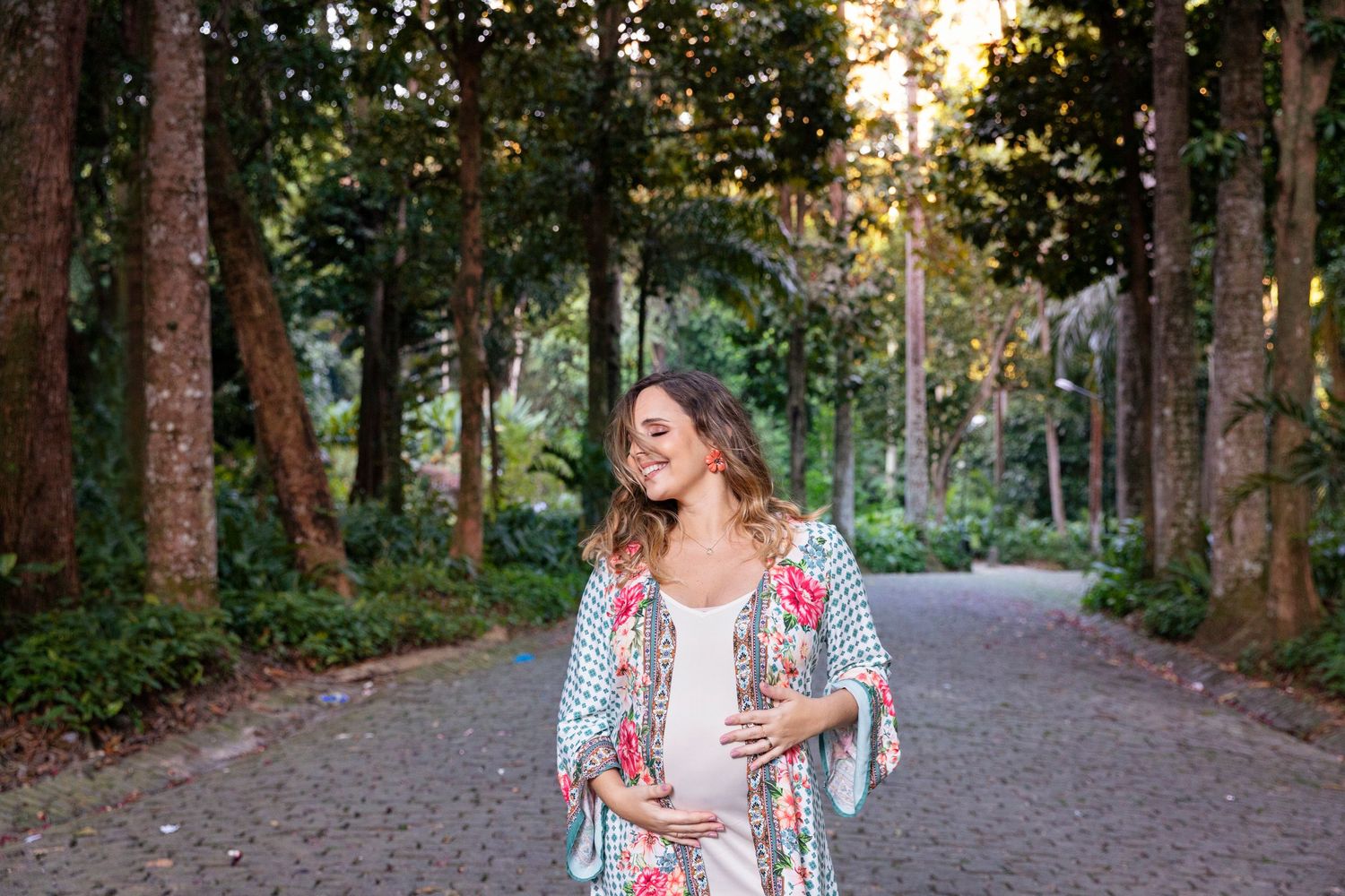Woman in floral dress walking along a tree-lined path at sunset.