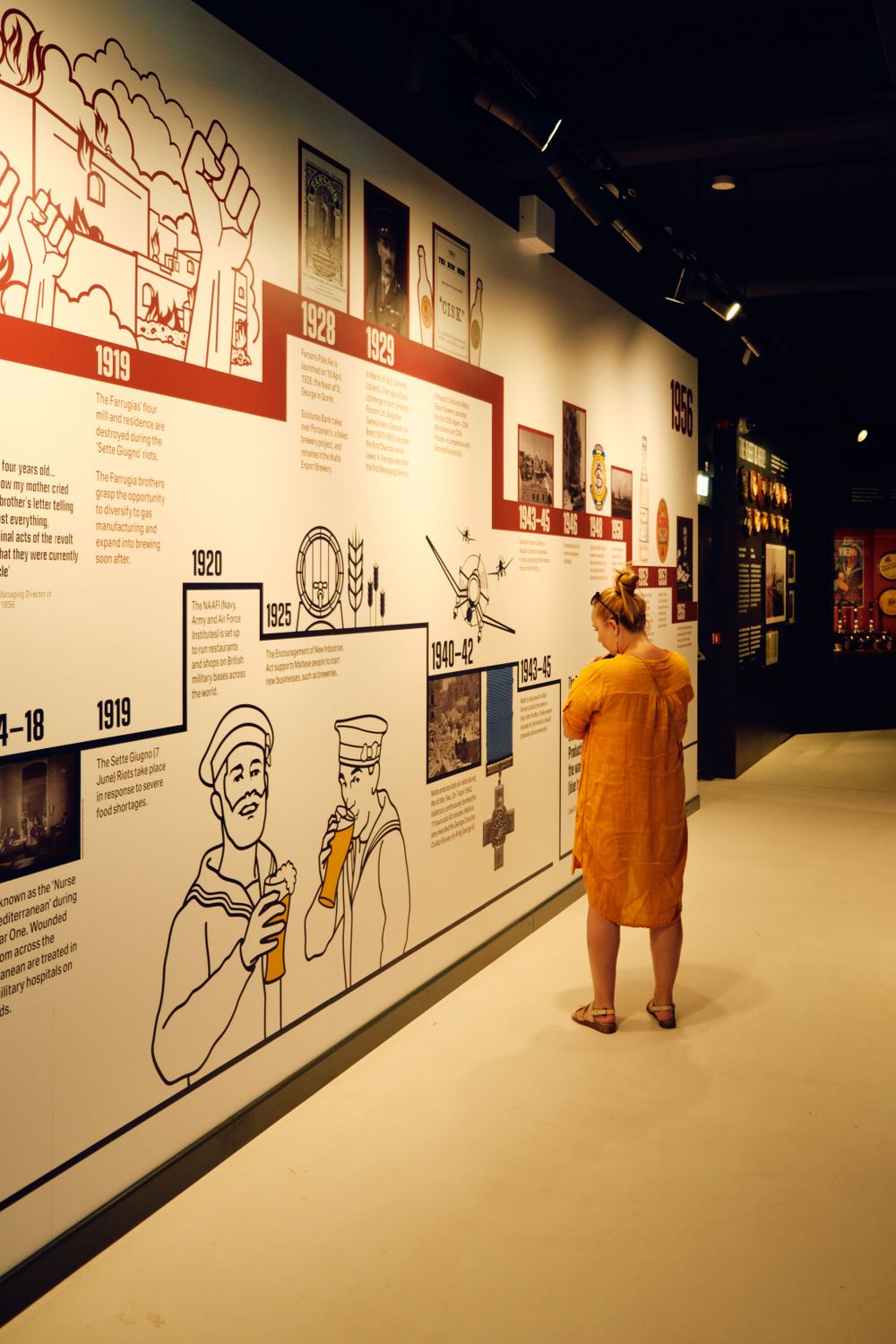 Museum visitor viewing timeline wall exhibit with illustrated beer history.