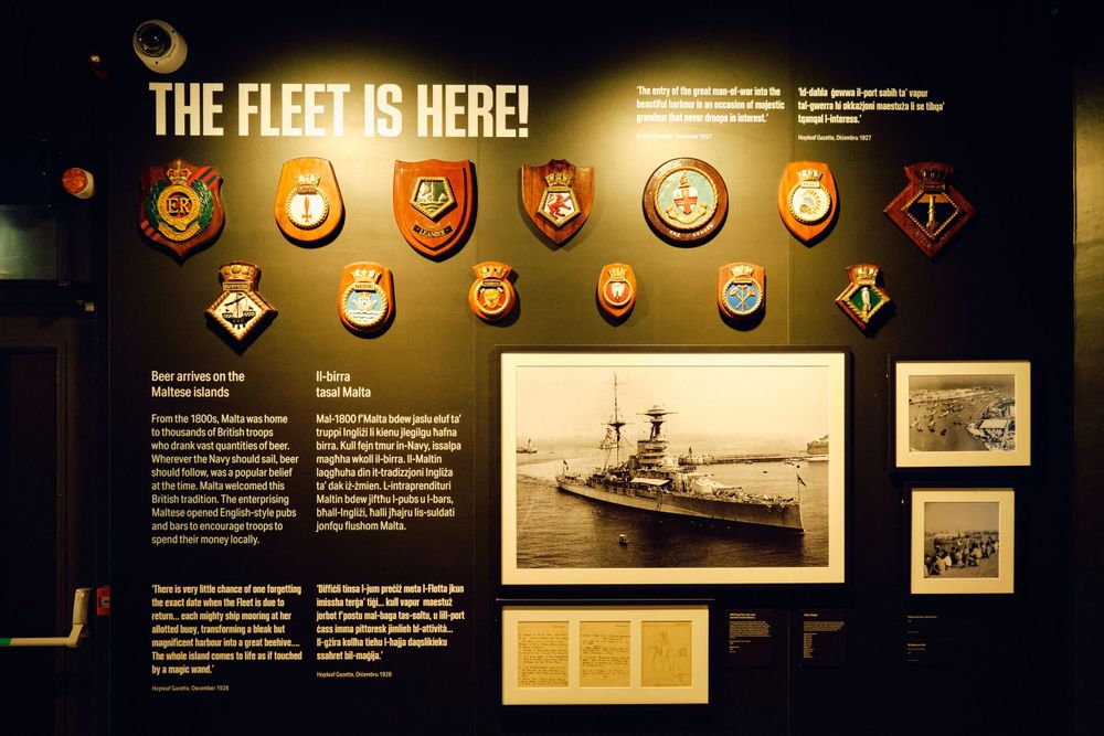 Naval fleet exhibit wall displaying military badges and vintage warship photographs.