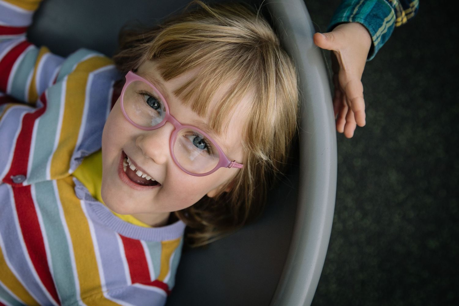 Joyful expression captured from above showing colorful striped clothing and glasses.