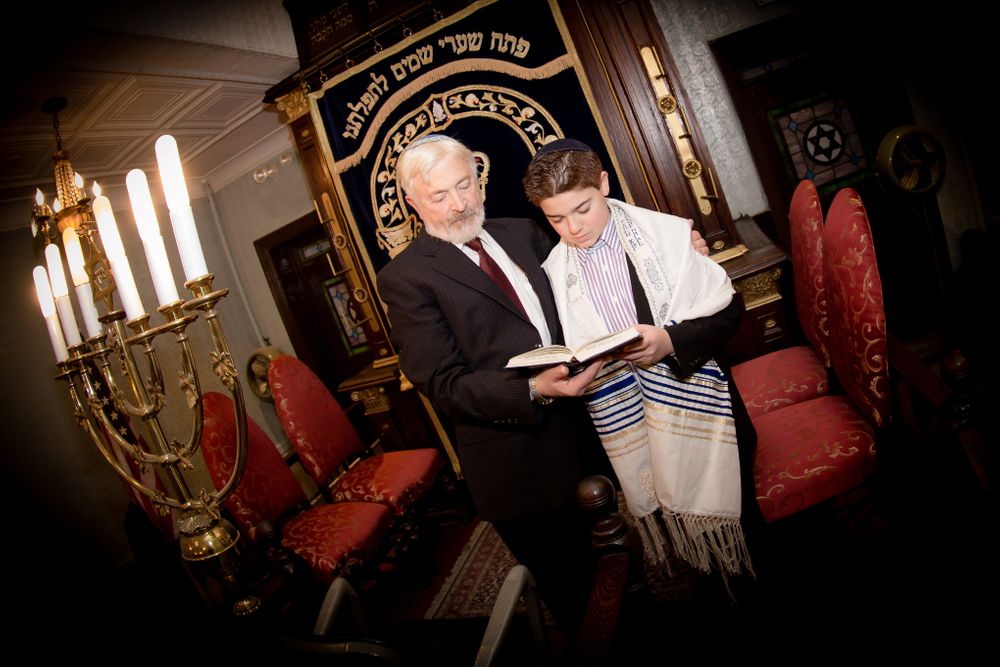 Religious ceremony taking place in synagogue with traditional decor and menorah.