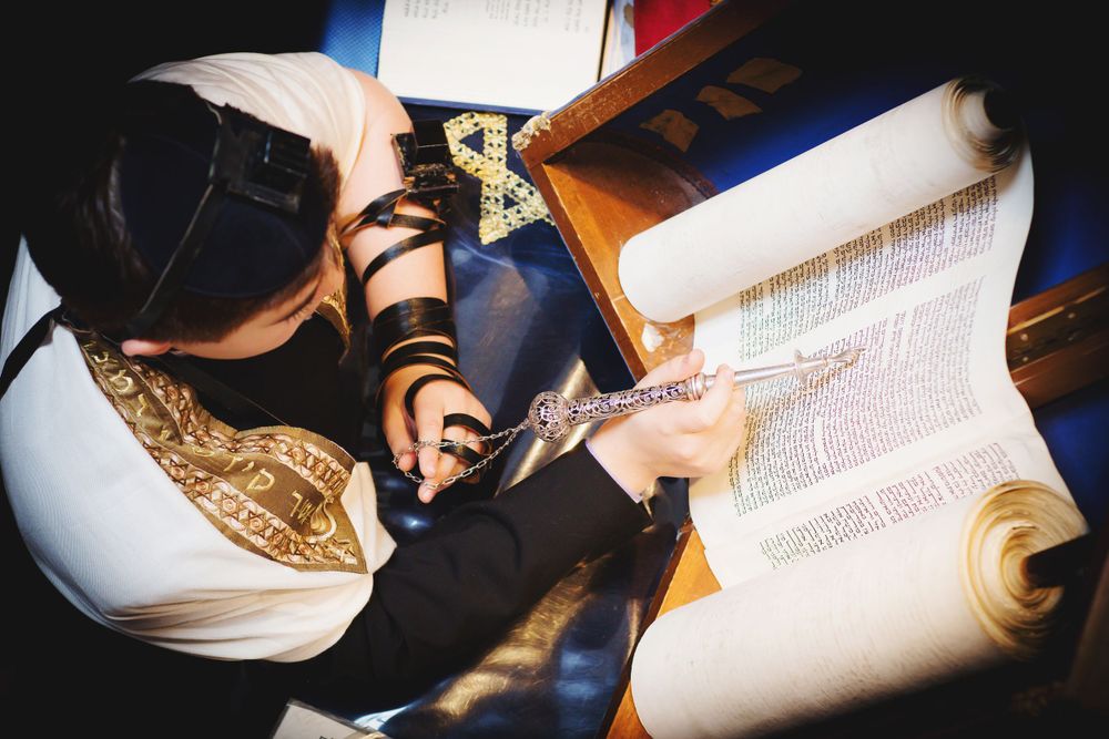Overhead view of person reading from Torah scroll during traditional Jewish ceremony.