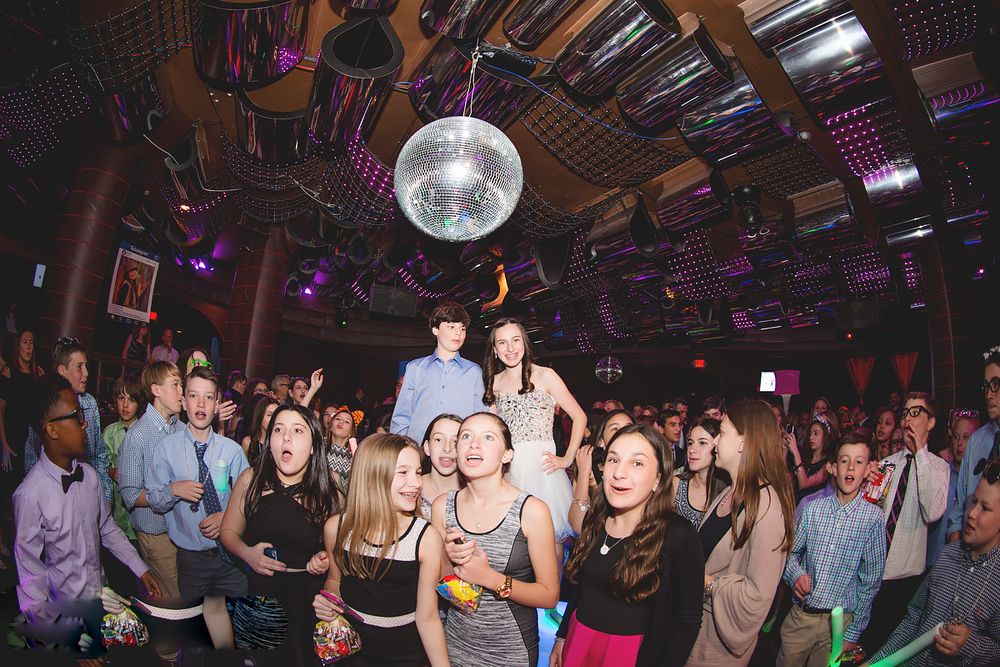 Crowded dance floor under disco ball at nightclub celebration party.