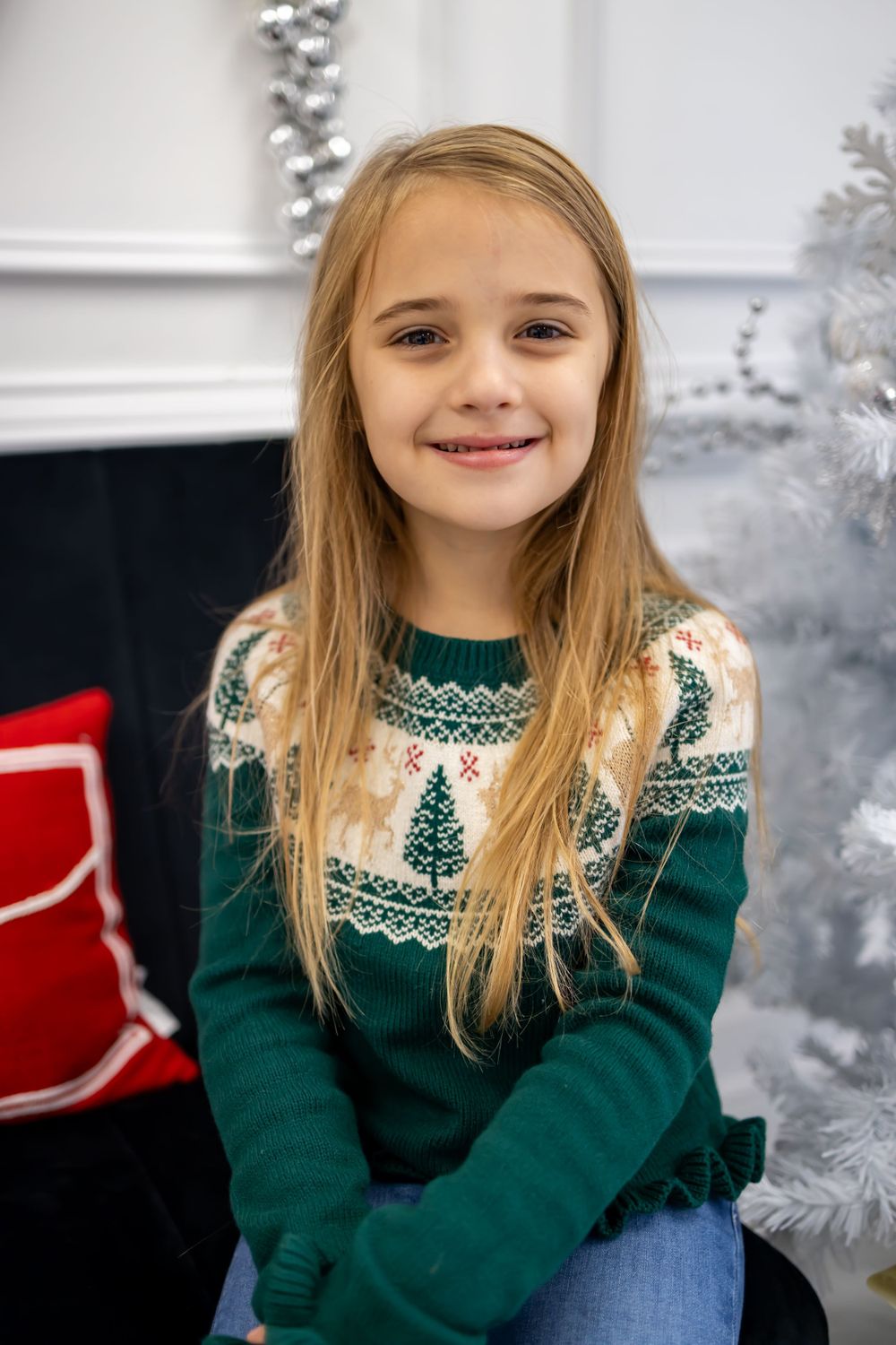 little girl smiling with green sweater for christmas picture