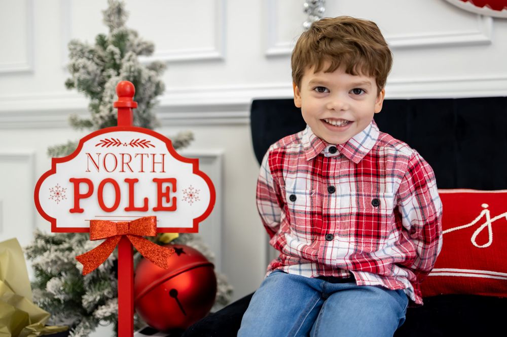 boy smiling with north pole sign for christmas