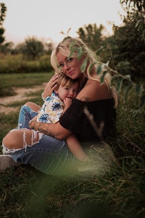 A candid moment captured in a garden setting shows affectionate embrace in casual summer attire.