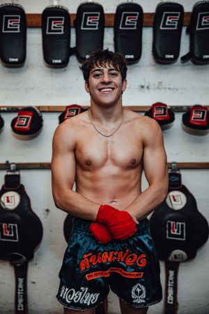 Training equipment and punching bags line the walls of a martial arts gym.